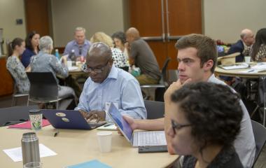 A student and two OUE staff listen attentively at table