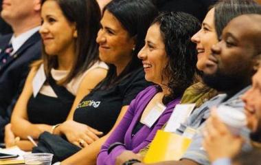 staff laugh in seats at symposium