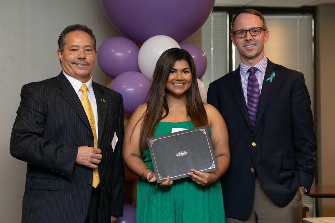 Staff stand with a student holding an award